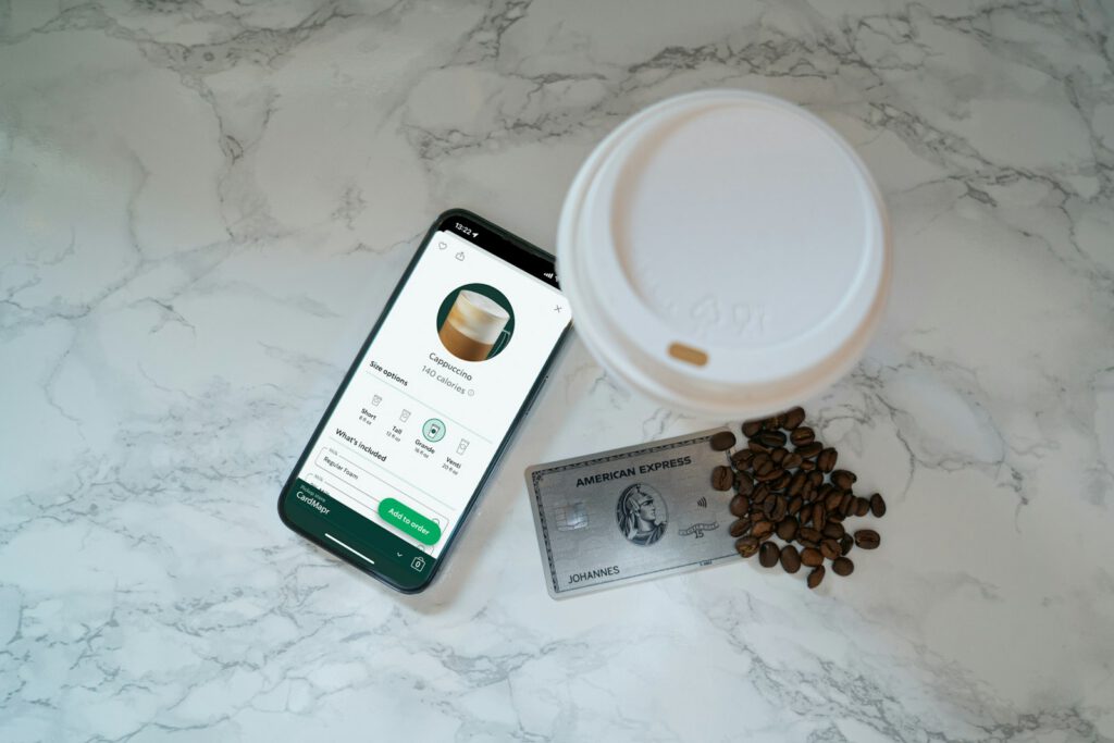 Smartphone avec application de fidélité près d’un café – illustration de l’article « Applications de fidélité : un levier pour les commerces de proximité », blog Ionia Web