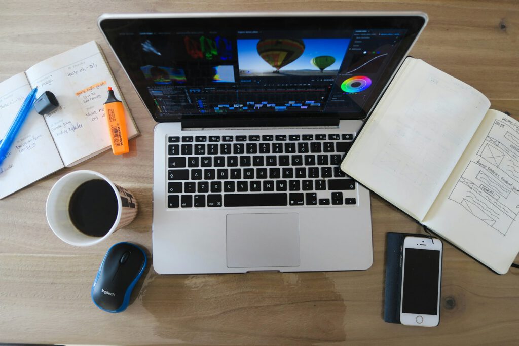 Bureau avec ordinateur portable, carnet et café – illustration de l’article « Nouveau : la création de visuels pour les réseaux sociaux », blog Ionia Web